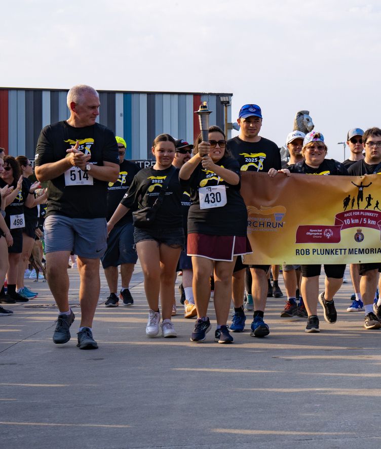 Deputy Chief walking with Special Olympic athletes and the flame of hope torch.