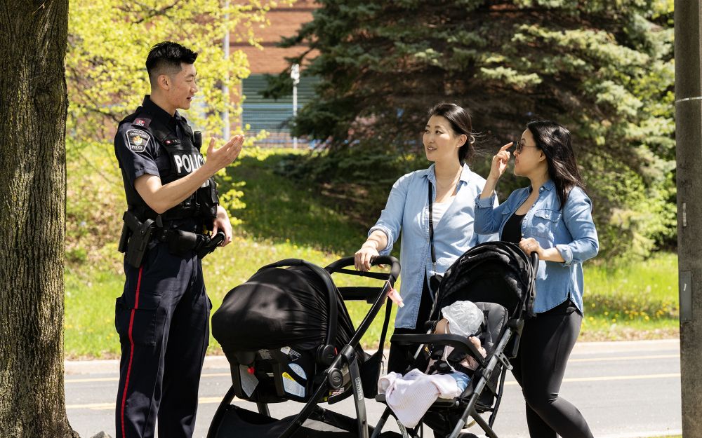 An officer speaks to two women pushing strollers