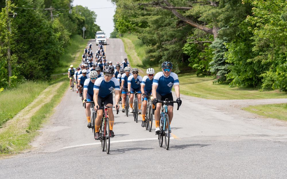 A group of cyclists ride in a line on a closed road