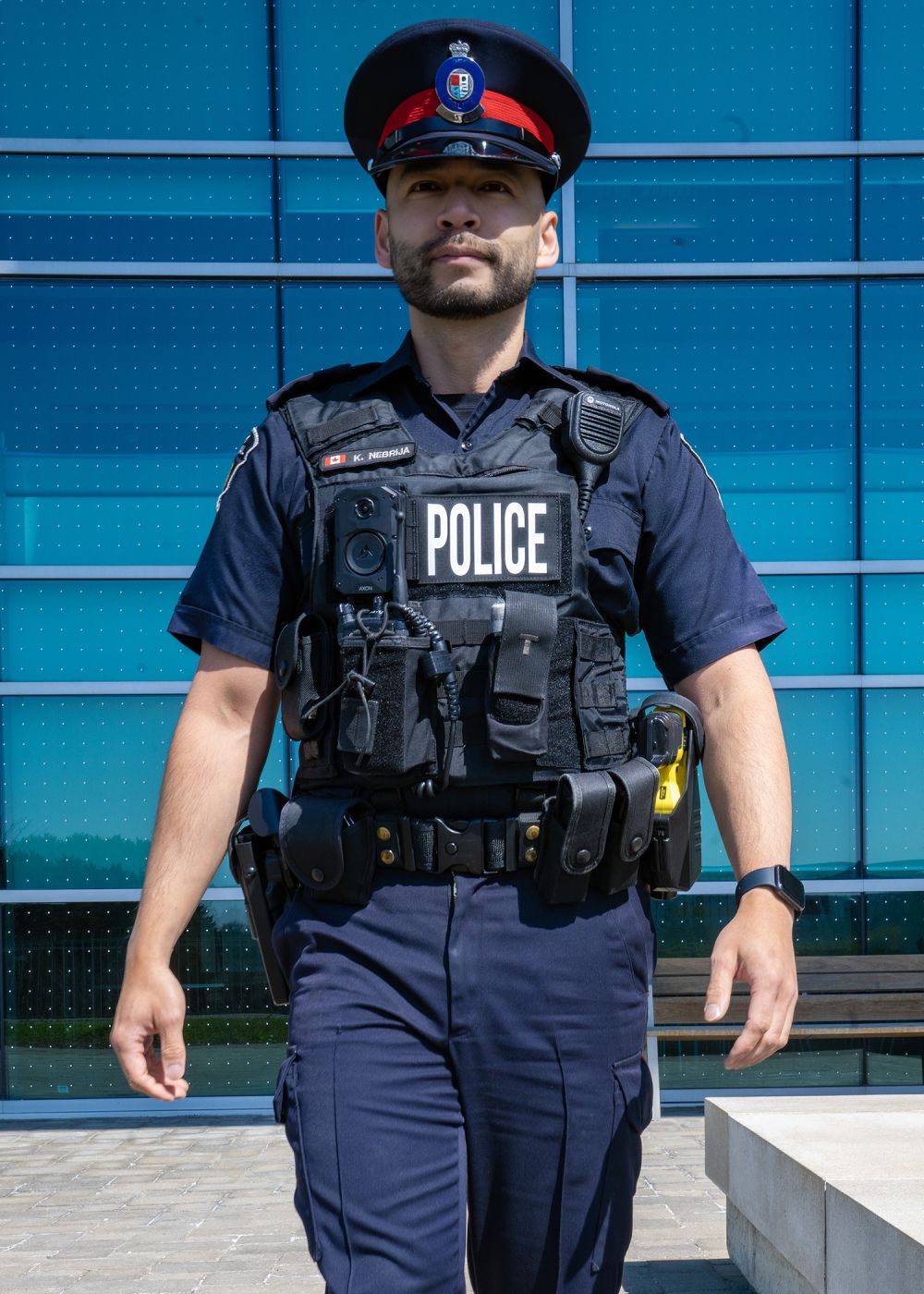 A man in a police uniform wears a vest with a camera mounted to it