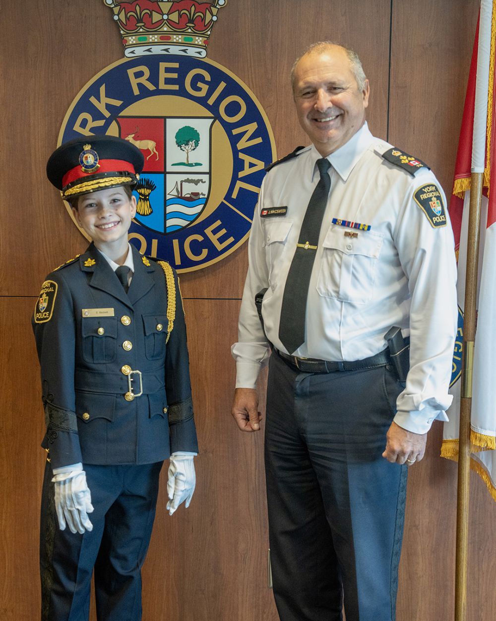 Chief for a Day essay contest winner Ella Beckett poses for a photo with Chief MacSween in front of the YRP crest