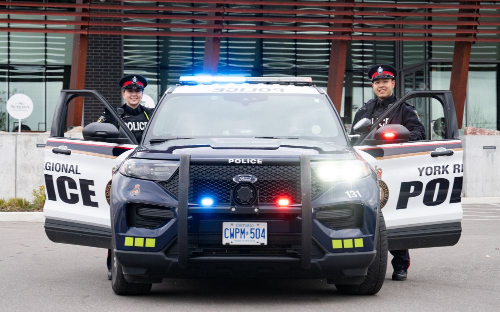 police car with open doors and officers behind them