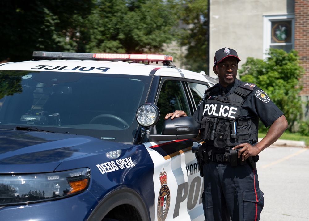 A man in a police uniform next to a police cruiser