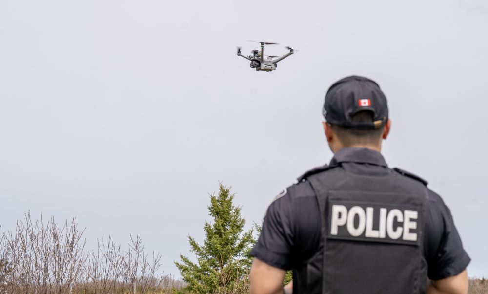 A drone flies above a man in a police uniform