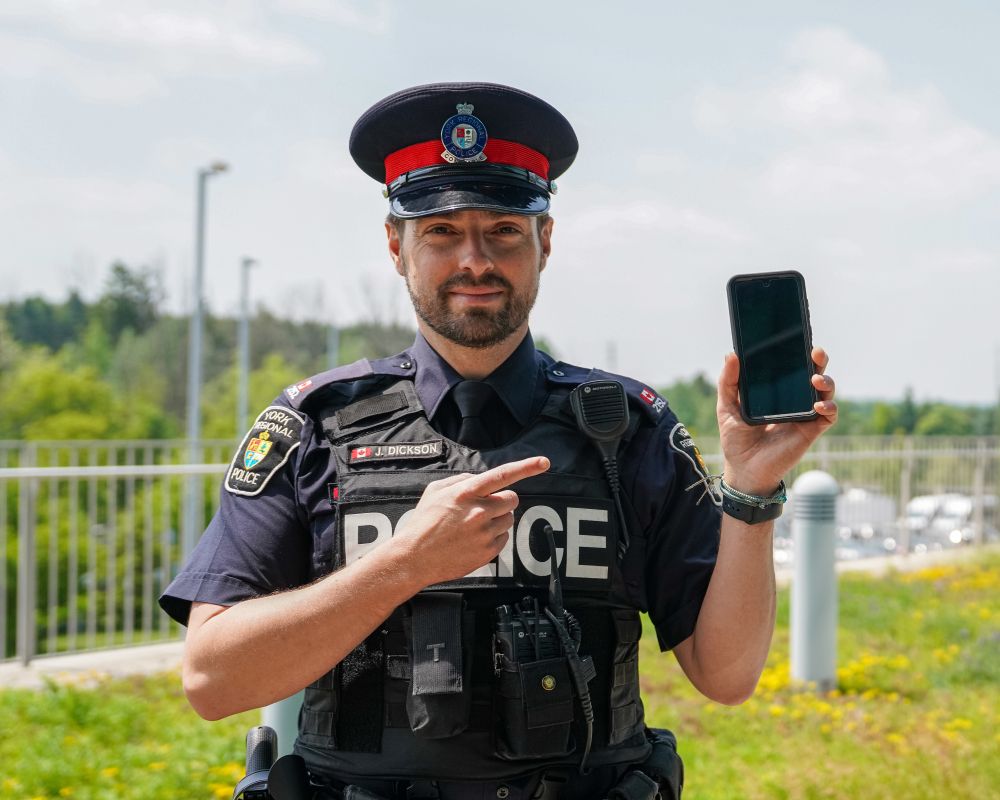 A man in a police uniform holds a phone