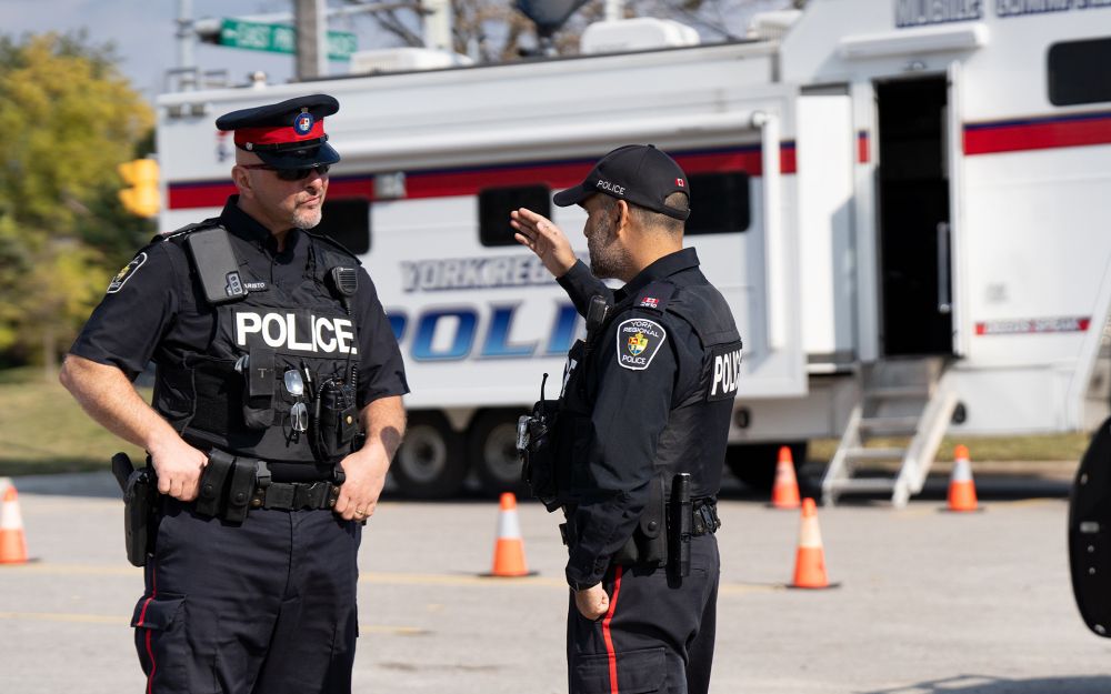 Two officers speak in front of the mobile command centre.