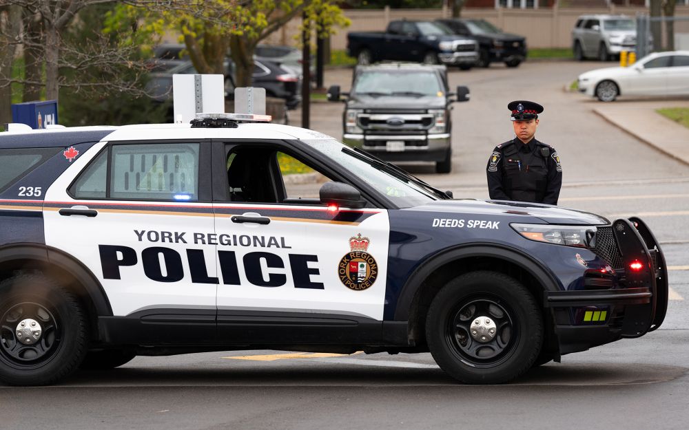 A man in a uniform stands next to a police vehicle