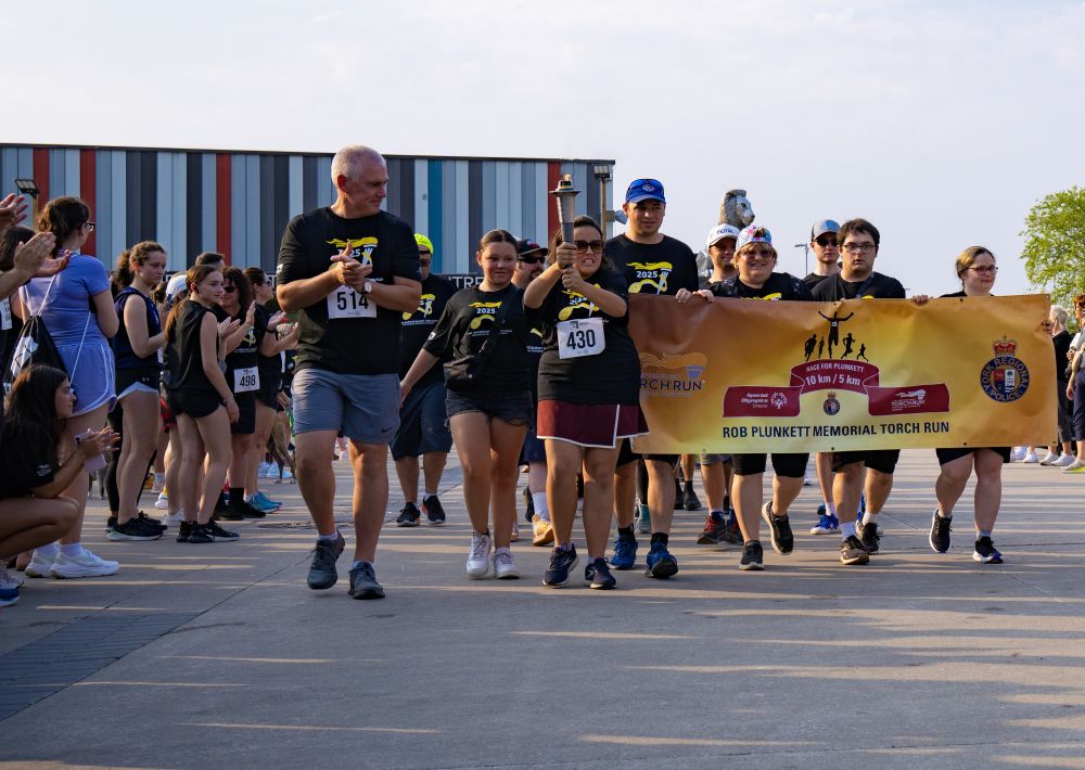 Deputy Chief walking with Special Olympic athletes and the flame of hope torch.