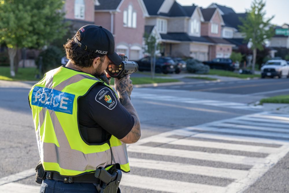 An officer conducts radar enforcement near a stop sign in a neighbourhood