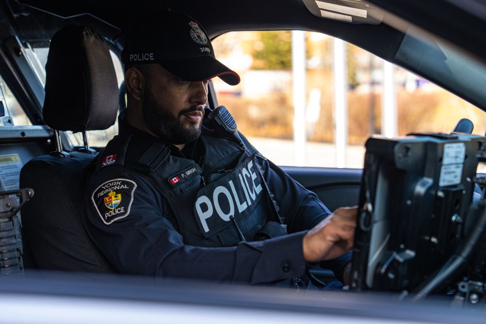 Police officer using in-cruiser laptop while parked.