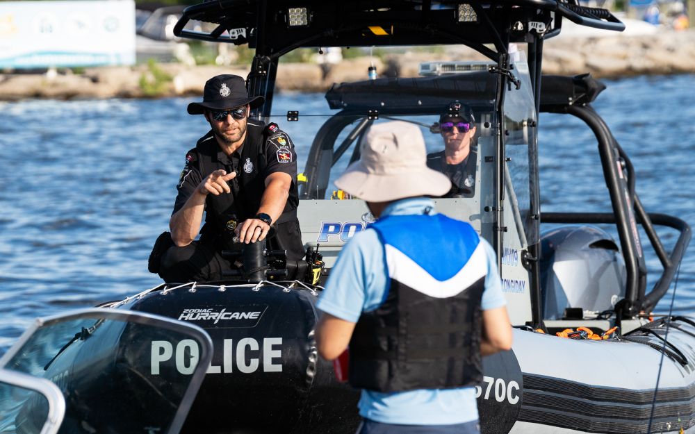 A man in a police uniform speaks to another man from a boat