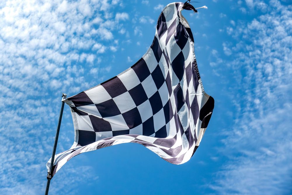 a checkered flag waves in the wind with a blue sky in the background